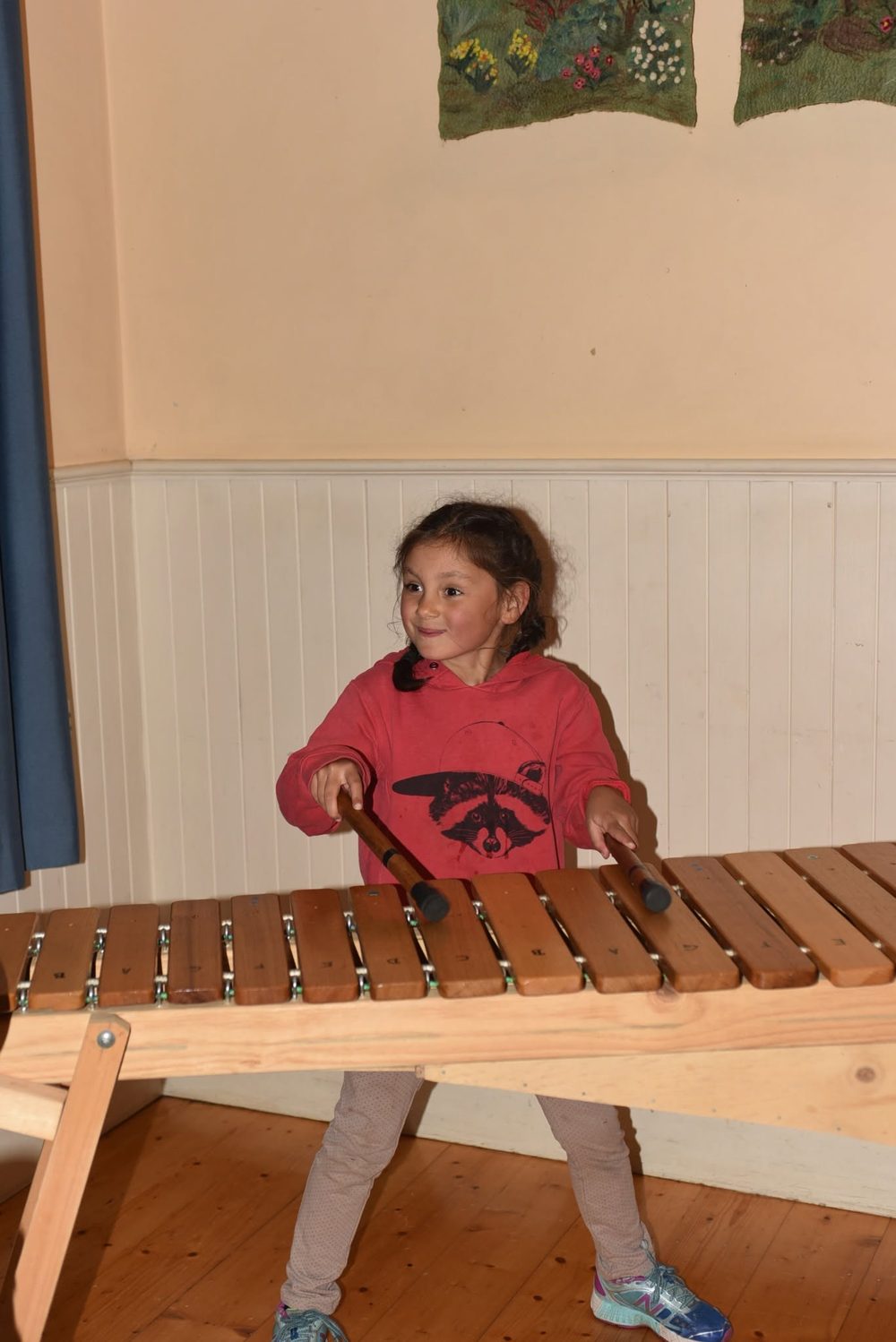 A young student smiling while playing a large wooden marimba